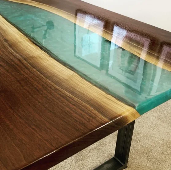 Custom live edge resin river dining table with black resin and natural wood grain on modern metal legs.