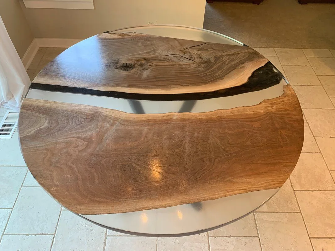 Round table with contrasting wood sections and a resin strip divider, combining dark and light wood grains for a modern artistic design.
