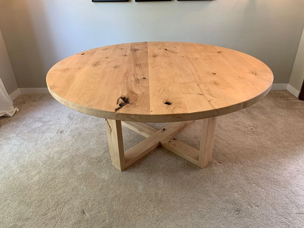Round rustic wood table with Open Loop base, photographed against a dark studio wall.