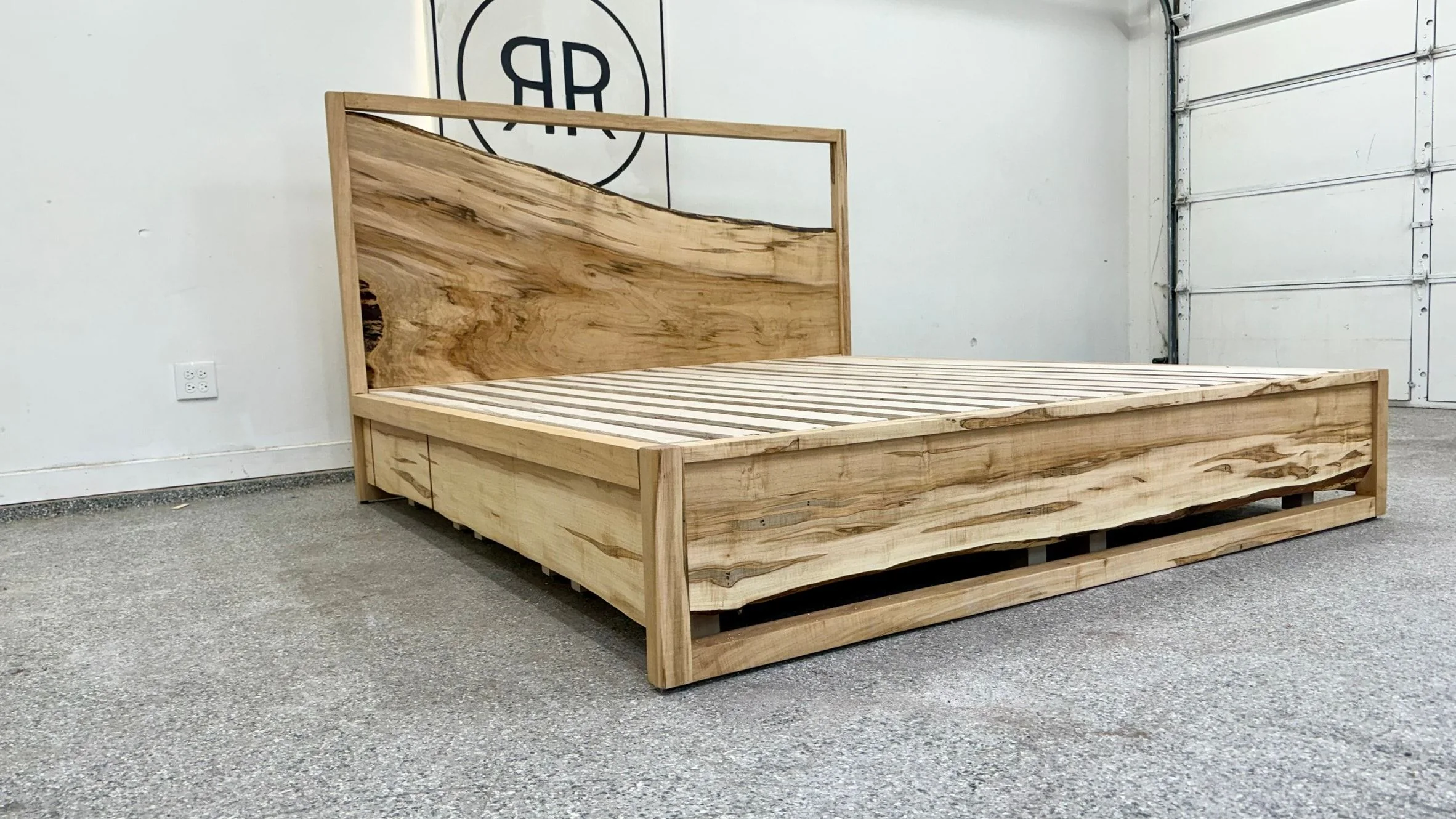 A light wood bed frame with a live edge headboard, in the workshop.