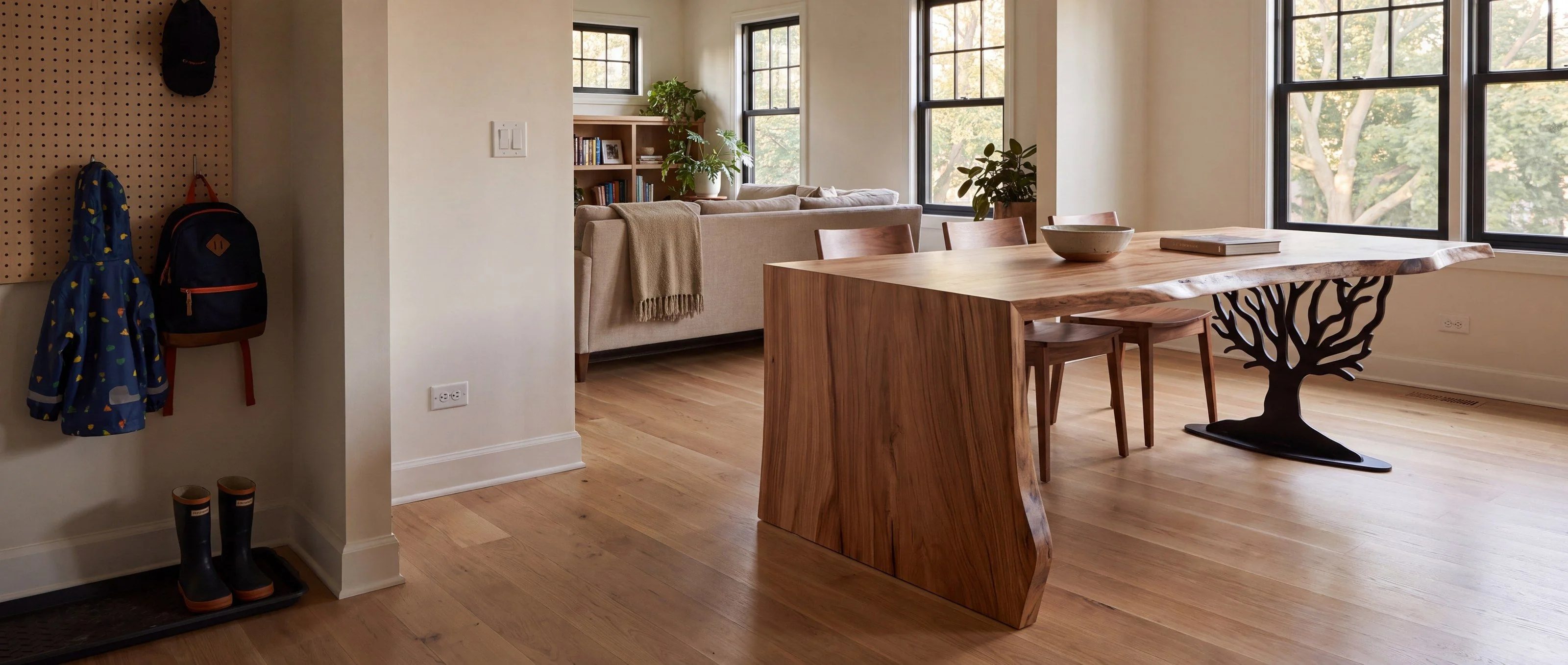 A rendering of a live-edge waterfall table with a steel tree base, one of Rob's pieces, in an open-plan family room in daylight.
