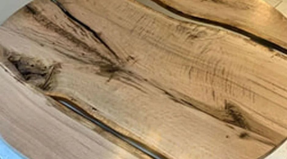 Round rustic wooden table with natural wood grain and visible cracks, displayed indoors on a tiled floor.