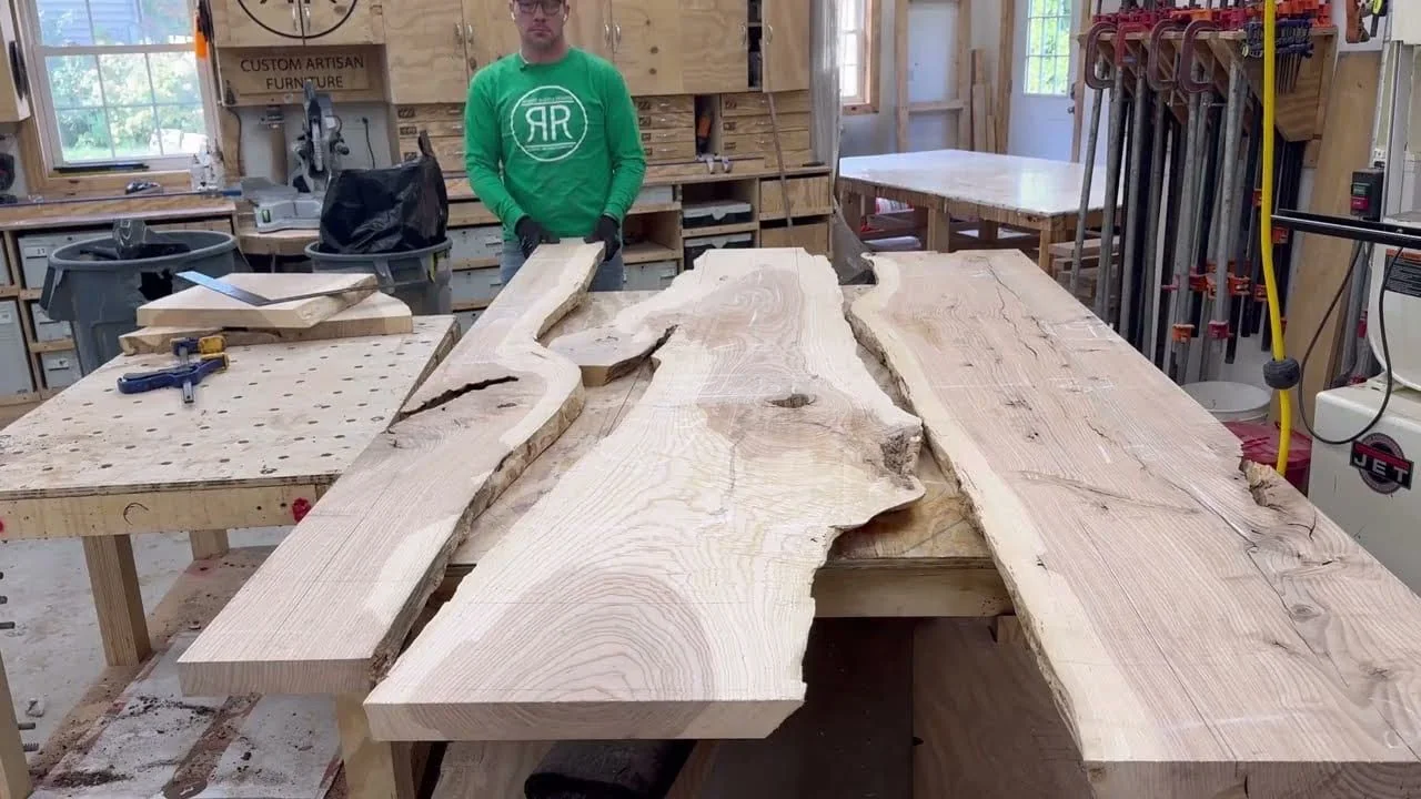 Rough hardwood slabs stacked on edge in the studio, waiting to be selected.